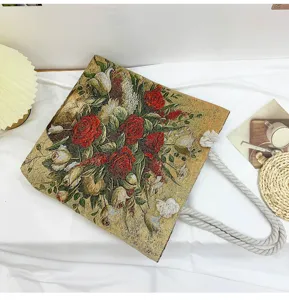 Vue détaillée d'un sac à épaule rétro à fleurs brodées avec des poignées en corde épaisse.