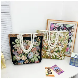 Vista detallada del bolso tote de lona floral tejida con asas de cuerda gruesa y amplia.
