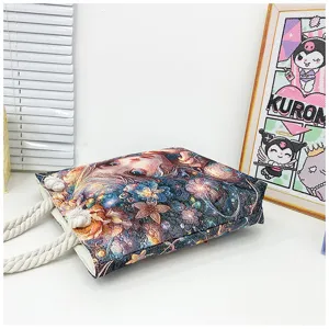 Vista detallada del bolso tote de lona con estampado de retrato floral y asas de cuerda en mesa.
