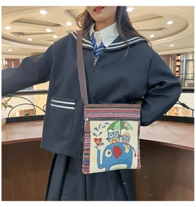 Sac bandoulière en toile style ethnique avec broderie d'éléphant et poches multiples.