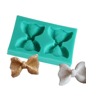 Detailed view of DIY bow silicone mold with gold and white finished fondant decorations.