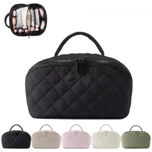 Quilted travel cosmetic bag with compartments and top handle for makeup storage and organization.