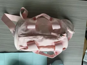 Vue détaillée du sac de sport cylindrique rose montrant la fermeture éclair et les anses.