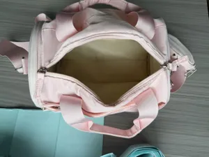 Sac de voyage cylindrique rose avec intérieur spacieux et petite pochette latérale de sport.
