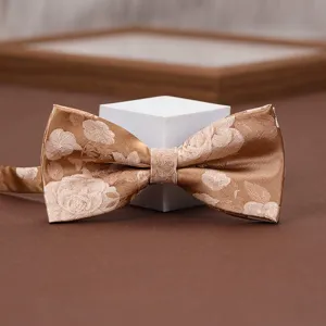 Close-up shot of a chic champagne gold patterned bow tie with delicate floral jacquard detail.