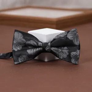 Classic black men's bow tie with grey floral pattern, elegant wedding suit accessory.