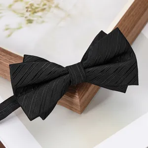 Black bow tie detail featuring multi-layer pleated texture and elegant wooden frame background.