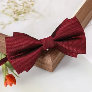 Gros plan du nœud papillon bordeaux mettant en valeur le tissu texturé et le style de mariage.