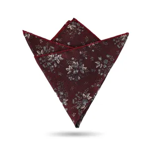 Primer plano detallado de un pañuelo de bolsillo burdeos con motivos florales y bordes.