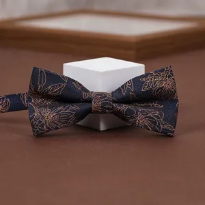Close-up detail of a navy blue bow tie featuring intricate golden floral patterns.