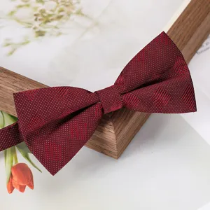 Gros plan détail d'un nœud papillon bordeaux à motif avec fine texture géométrique.