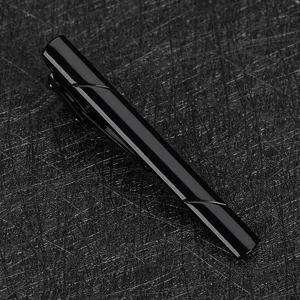 Détail de pince à cravate noire en métal, accessoire élégant pour homme au fini brillant et épuré.