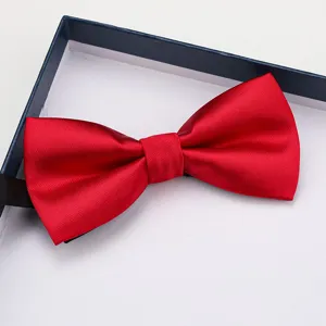 Detailed close-up of a vibrant red satin bow tie with black strap neatly placed in gift box.