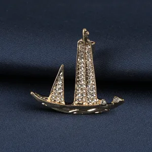 Erhöhte Detailansicht einer goldenen Segelboot-Brosche mit funkelnden Strasssteinen für Herren.