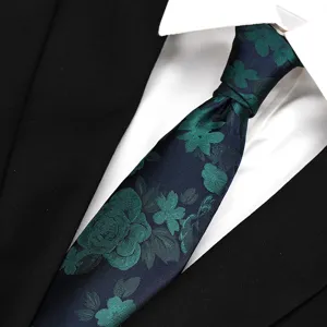 Close-up detail of mens navy blue silk tie with elegant green floral jacquard pattern.