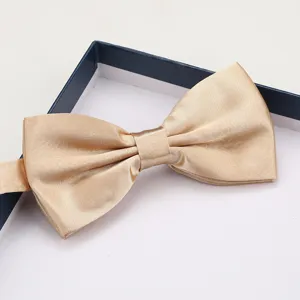 Closeup of elegant champagne satin bow tie in gift box, premium groom formal wear detail.