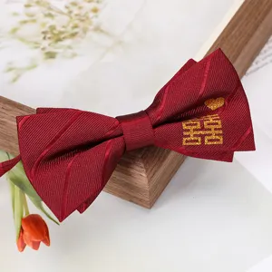 Gros plan détaillé d'un nœud papillon de mariage bordeaux avec broderie dorée double bonheur.