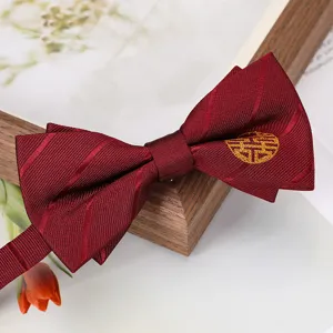 Gros plan sur le nœud papillon bordeaux de mariage avec broderie dorée de double bonheur.