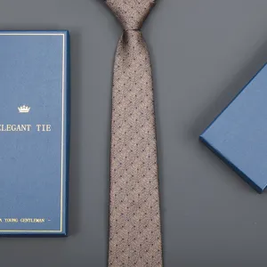 Close-up detail of a classic brown dotted men tie paired with a luxury blue gift box.