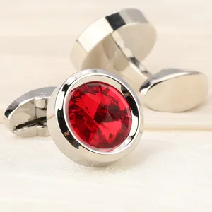 Gros plan de boutons de manchette en cristal rouge avec métal argenté et pierres facettées.