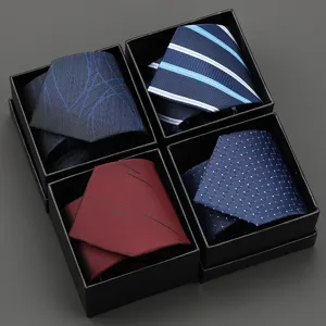 Detailed view of four classic mens neckties with assorted patterns inside black gift boxes.