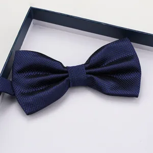 Close-up of dark blue grid bow tie in gift box showing fine fabric texture and neat folding detail.