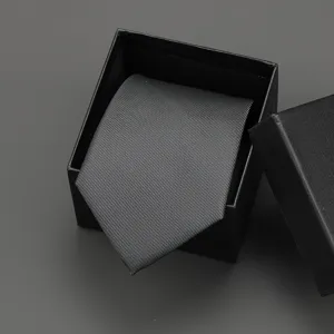 Detailed close-up of a stylish black striped necktie neatly displayed inside a black gift box.