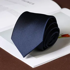 Close-up detail of a rolled navy blue twill men formal business necktie on desk scene.