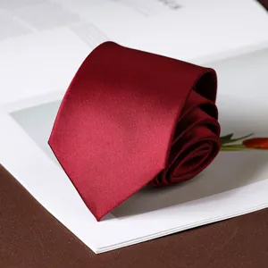 Classic dark red business necktie rolled up nicely on a decorative book background.