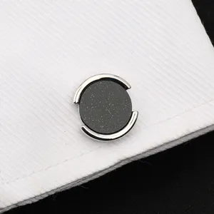 Gros plan détaillé de boutons de manchette ronds en argent avec incrustation de grès noir.