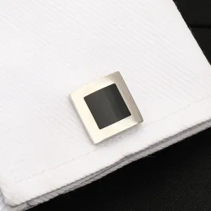 Gros plan détaillé de boutons de manchette carrés en métal élégants pour homme noirs.
