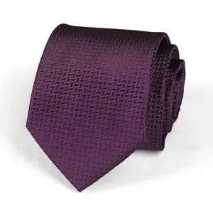 Burgundy patterned tie close up detail showing textured fabric and elegant rolled shape presentation.