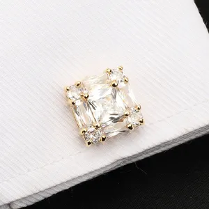 Gros plan détaillé d'un bouton de manchette en cristal carré sur un tissu blanc texturé.