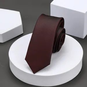 Primer plano de una corbata estrecha burdeos con textura fina expuesta en podios blancos.