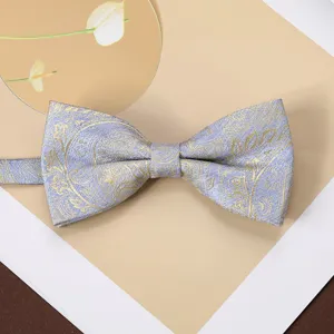 Men's retro jacquard bow tie detail, elegant gold paisley pattern on light blue fabric.