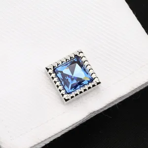 Détail en gros plan d'un bouton de manchette carré en cristal bleu pour homme élégant.