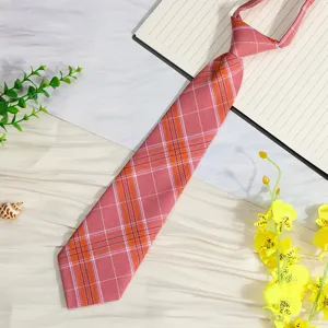 Detailed close-up of the pink and orange plaid school uniform tie showing fine fabric texture pattern.