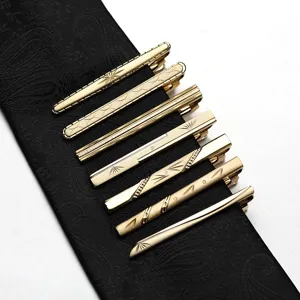 Detailed close-up of golden metal tie clips featuring various elegant engraved textures.