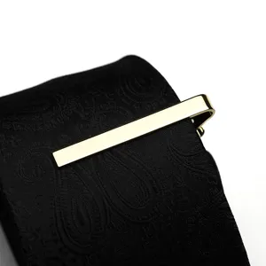 Gold tie clip detail shot showcasing elegant metallic shine on classic patterned black tie.