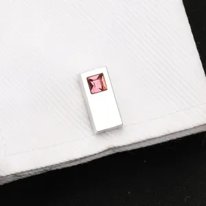 Gros plan détaillé d'un bouton de manchette argenté avec cristal rose sur une manchette de chemise.