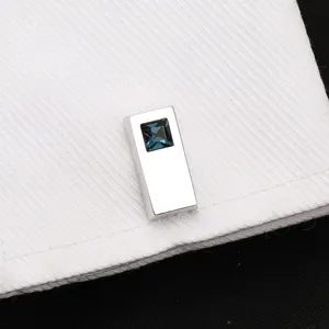 Vue rapprochée d'un bouton de manchette argenté avec un cristal bleu sur une chemise.