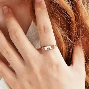 Bague ouverte minimaliste en or rose gravée de lettres, détail de bijou pour index.