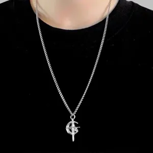 Gros plan détaillé d'un élégant collier pendentif croix et croissant de lune argenté sur haut noir.