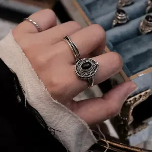 Anello medaglione vintage in argento con pietra nera e motivo filigranato, vista dettagliata.