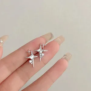 Close-up detail of shimmering zircon star earrings featuring delicate asymmetrical four-pointed star design.