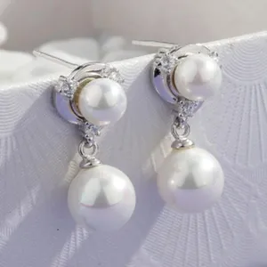 Detailed close-up of elegant double-layer pearl stud earrings with sparkling cubic zirconia.