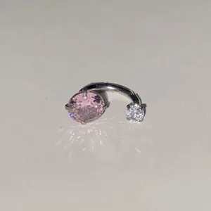 Λεπτομερές κοντινό πλάνο του λαμπερού piercing πετάλου με μεγάλο ροζ κρύσταλλο και πέτρα.