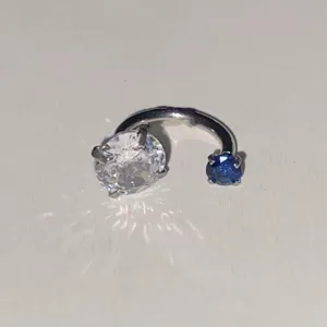 Λεπτομερής λήψη ασύμμετρου piercing πετάλου κρυστάλλου με διαυγείς και μπλε πέτρες.