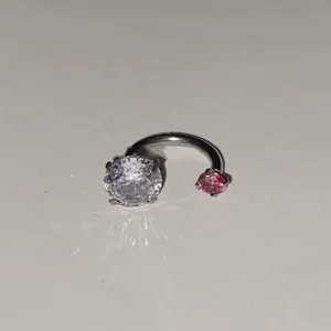 Λεπτομερής όψη κομψού σκουλαρικιού piercing σε σχήμα πέταλο με μεγάλη διαφανή και ροζ ζιρκονία.