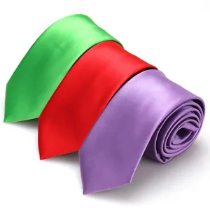 Primer plano detallado con tres corbatas estrechas lisas enrolladas en verde, rojo, morado.